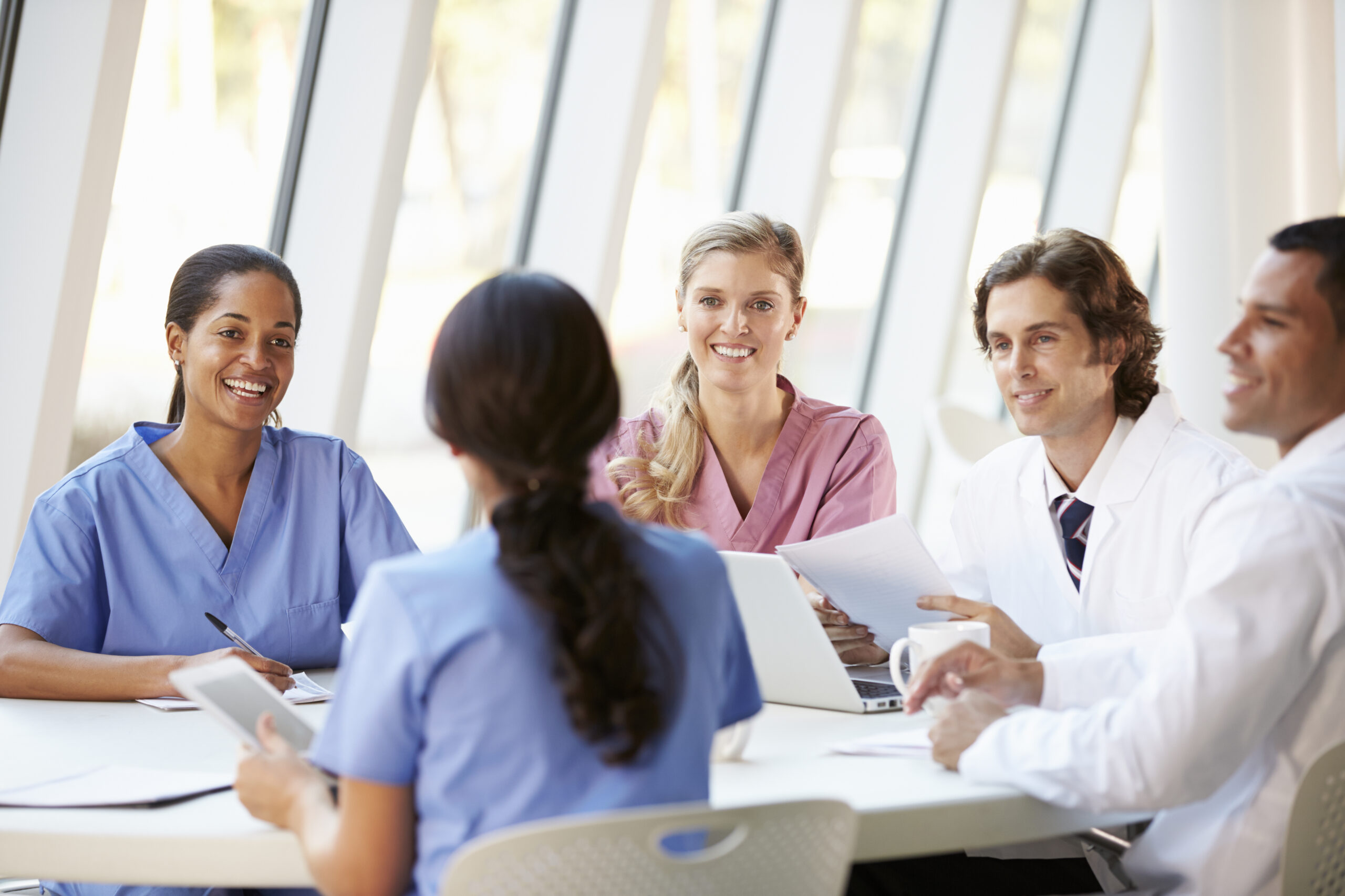 Medical Team Meeting Around Table In Modern Hospital